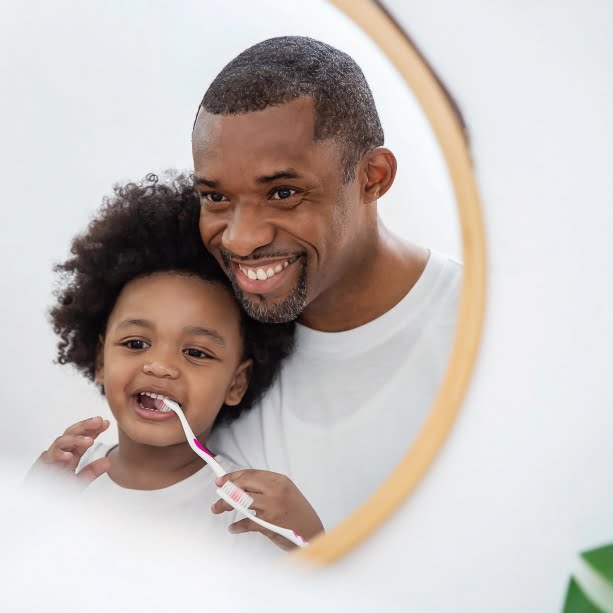 Portrait of happy family black African American father son child boy brushing teeth in bathroom. Morning routine with toothbrushes, father’s day